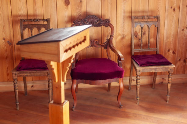 An armchair on a wooden floor, a radiator behind it and a ray of sunlight coming from a window