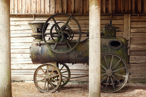 View of the antique rusty agricultural locomobile. steam train or tractor. Made in England. steam tractor standing in a field. Vintage Steel Wheel Farm tractor. Purpose to to work in a forest sawmill.