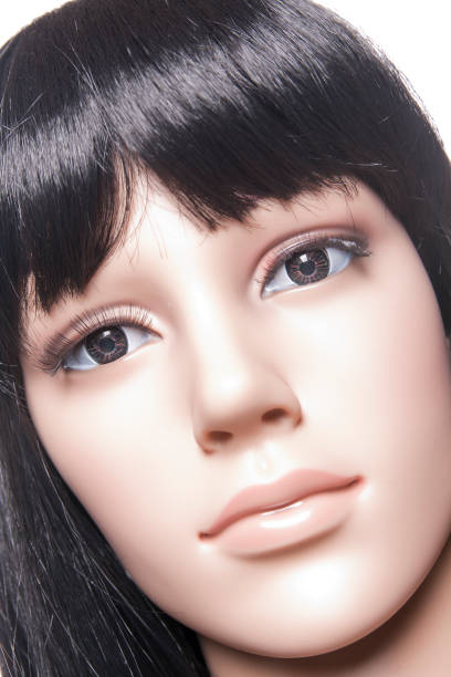 Plastic woman mannequin closeup with black long hair posing on a white background in a high key setup