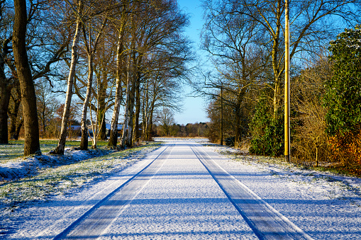 A car tire mark on fresh snow on the asphalt in winter on a road leading to a dead end. Winter road.