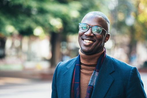 Shot of handsome african-american young man outdoors in the city. Portrait of a young African-American businessman looking at camera and smiling