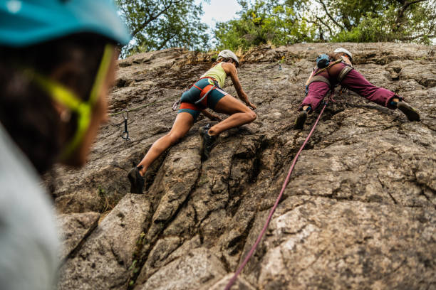 istock Female climbers climbing mountain together 1985635100