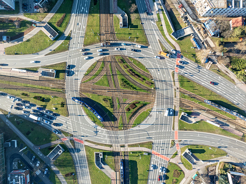 Traffic circle Rondo Czyzynskie in Krakow, Poland, with tramway crossing, three trams, three lane city roads, bicycle lanes, underground pedestrian crossings and cars. Aerial view from above