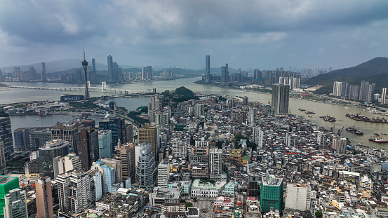 An aerial photograph capturing the expansive cityscape of Macao, featuring a river flowing through its urban landscape.