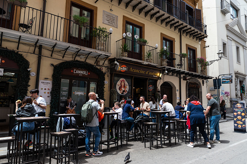 Palermo, Italy - May 13, 2023: Terrace of a restaurant bar in Via Maqueda with people around in the old town of Palermo, Sicily, Italy