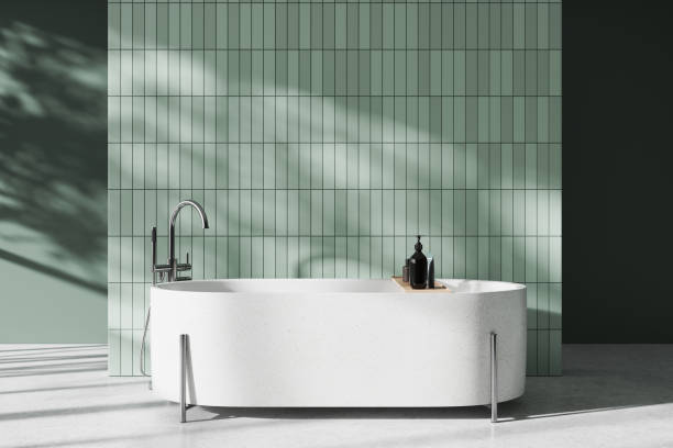 istock Green hotel bathroom interior with bathtub and accessories, empty tile wall 1985686675