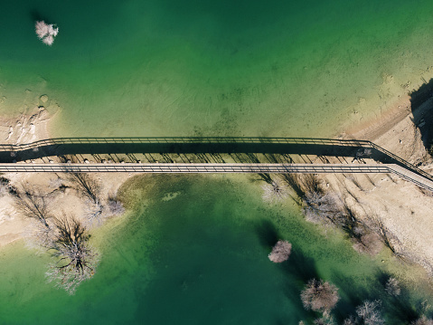 Wooden bridge connecting two shores in a lake area as seen from above