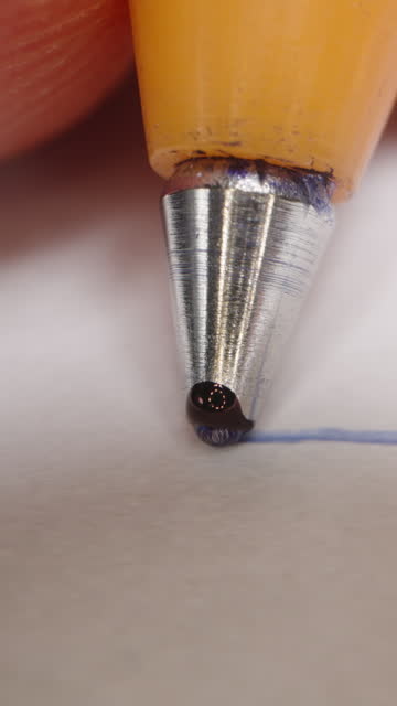 Vertical video. First-person view, the camera follows the ballpoint pen as the man draws a straight line. Dolly slider extreme close-up.