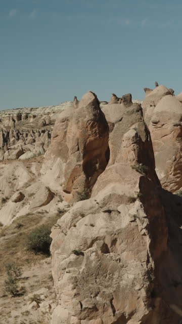 Vertical video. A first-person top-down view of the rocks and mountains in the Valley of Imaginations in Turkey, clear weather.