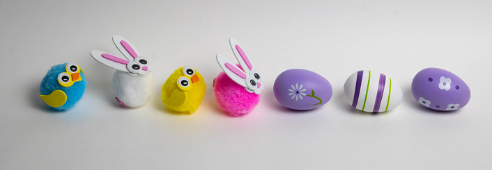 A panorama of lilac Easter eggs and small toys rabbits birds symbol of Easter.