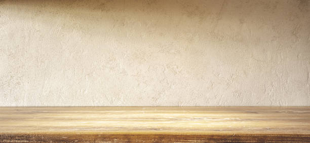 istock Empty Wooden Table Top With Textured Beige Wall Background in Soft Light 1985747998