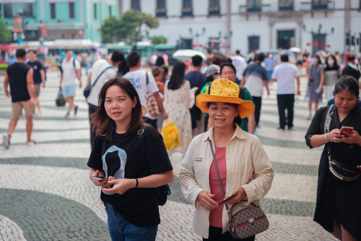 Macao, China - May 12, 2023: Two women walking side by side on a busy street in Macao.