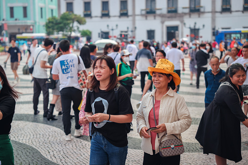 Macao, China - May 12, 2023: A diverse group of people walking down a bustling street lined with towering buildings in the city of Macao.