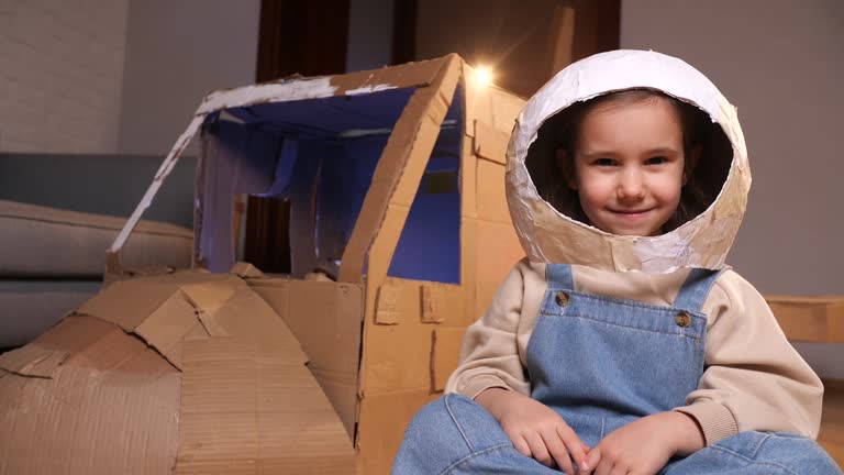 girl in an astronaut helmet looks at the camera and smiles