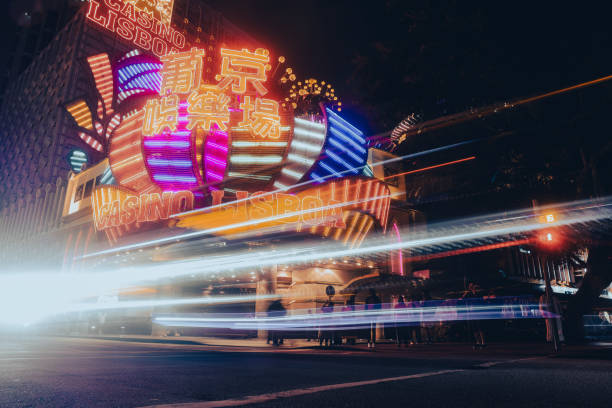Macao, China - May 12, 2023: A car with bright inscriptions drives down a city street at night in Macau, capturing the bustling urban atmosphere.