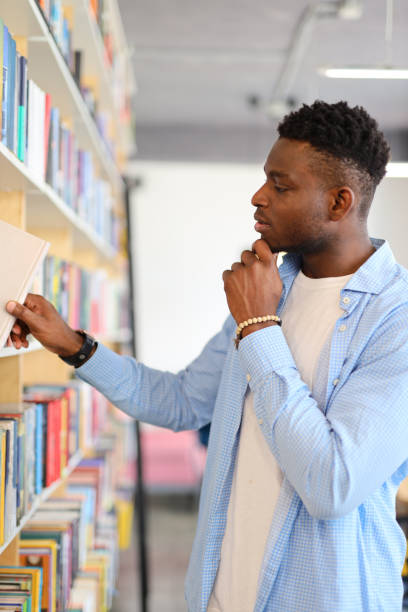 istock Serious young student in a library, contemplating book choices, immersed in academic pursuits and knowledge. 1985779342