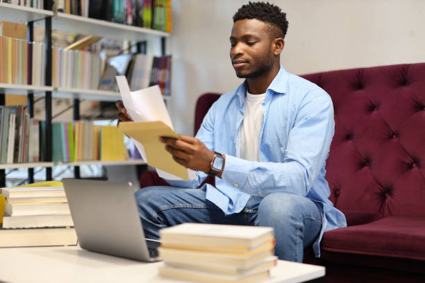 istock Casual young man at home, studying with a laptop and books, creating a comfortable learning space. 1985779869