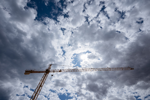 Sky-high crane piercing through a cloudy backdrop, epitomizing architectural ascent.