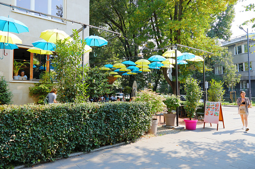 Warsaw, Poland - September 13, 2023: In the Saska Kepa housing estate, part of the Praga-Poludnie district, yellow and blue umbrellas were hung over an open-air cafe.