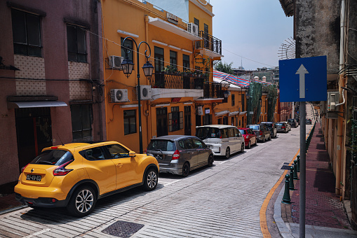 Macao, China - May 12, 2023: A yellow car is parked on the side of a Macau street.