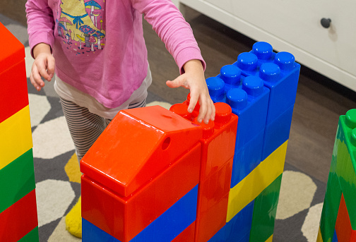 girl plays with drawn blocks of a constructor at home, A child's hand puts large colorful blocks from a children's model set