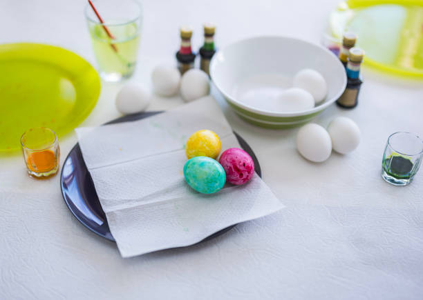 Close-up view of children's painted Easter eggs lying on a plate on the table.