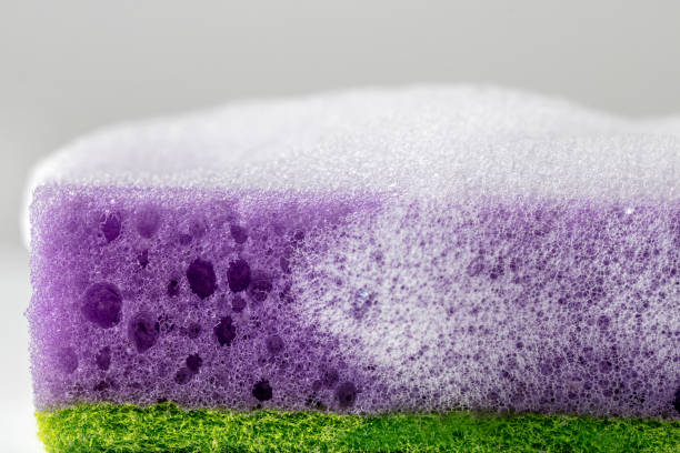 Close-up of a wet sponge for washing dishes with soap sud.