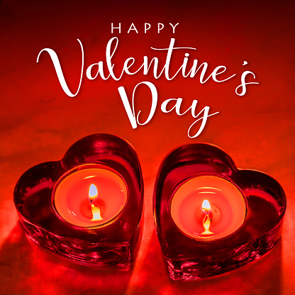 Two heart shaped burning candles with a HAPPY VALENTINE'S DAY lettering on a red background. Can be used as a design for Valentine's day holiday greeting cards or posters.