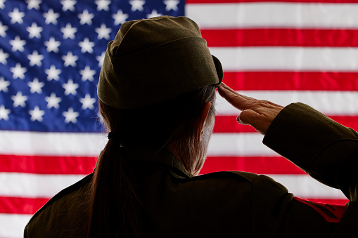 Female Soldier saluting the American Flag with shallow depth of field