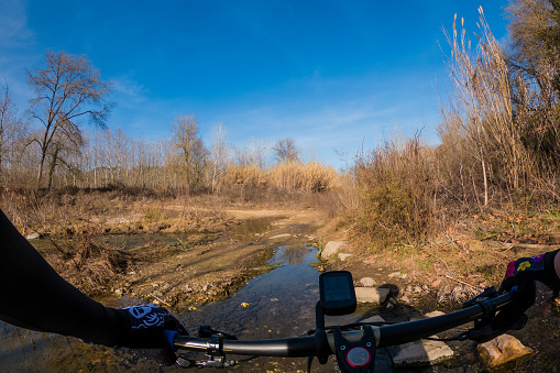 Crossing a water pond on a brown dry sunny landscape with a mountain bike