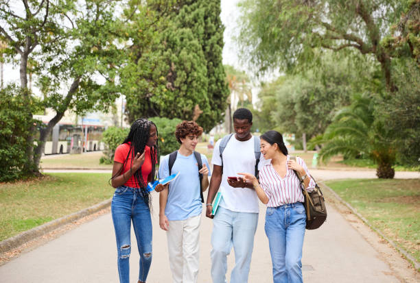 istock Group of multiethnic students walking down the street and using a smartphone 1985993422