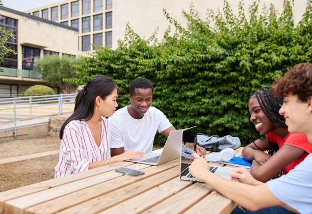 istock Multiethnic group of young students sitting outdoors and studying together on their laptops 1985994946