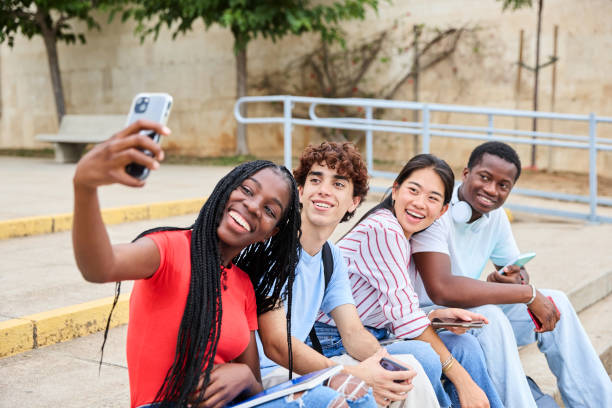 istock Cheerful young multiethnic students taking a selfie with their smartphone while sitting on the stairs outside the college on campus 1986001817