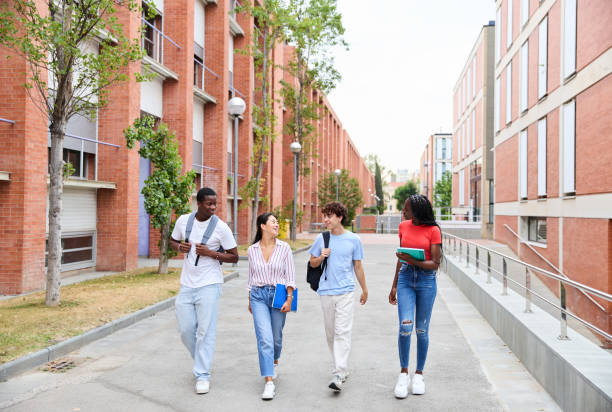 istock Multiethnic young students walking along university campus with books and backpack 1986006007