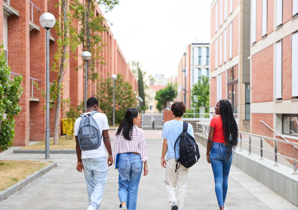istock Young group of diverse students walking on sidewalk on university campus 1986006528