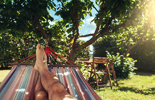 POV of summer relaxing and sunbathing on hammock: man feet while resting under a warm sun in Italy