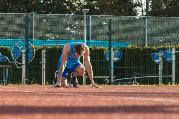 istock Sprinter assuming a start position in the starting block, rear view 1986035959