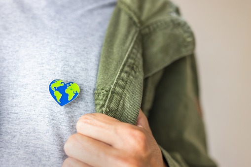 Heart-shaped Earth pin proudly worn on a person's chest, emphasizing love for our planet and the call to preserve it