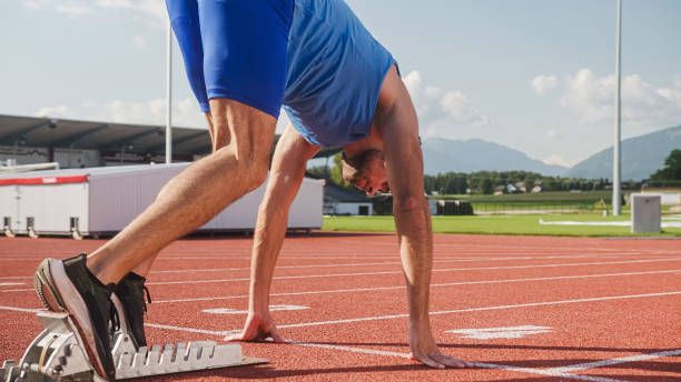 istock Male athlete preparing beyond start line and running 1986037188