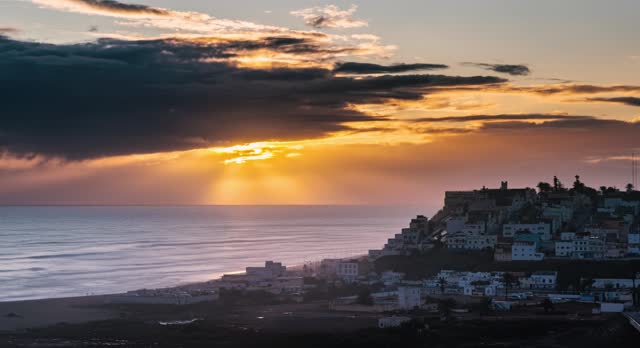 Golden sky sunset over ocean coast town in Morocco landscape Time lapse panorama