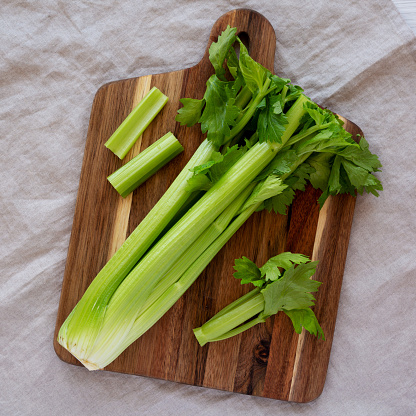 Fresh organic celery with roots on wooden table