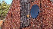Satellite TV Antenna Dish Mounted on Wall of Old Village Building Red Clay Brick Wall