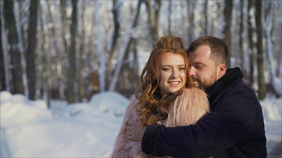 The guy and the girl have a rest in the winter woods. Husband and wife in the snow. Young couple walking in winter park