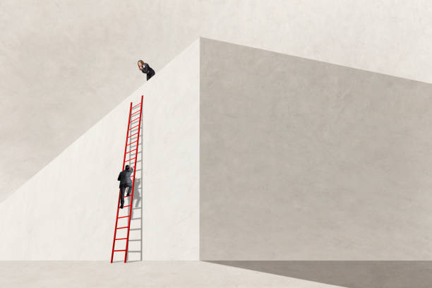 istock Woman Looking Down At Man Climbing On Ladder 1986073158