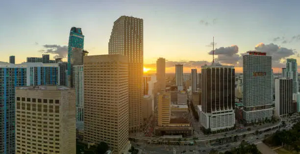 Evening urban landscape of downtown district of Miami Brickell in Florida USA. Skyline with dark high skyscraper buildings and street with cars and Metrorail traffic in modern american megapolis.