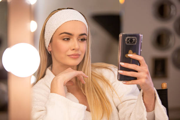 istock Confident Glamour: Beautiful Makeup Artist Admires Work on Phone 1986096577