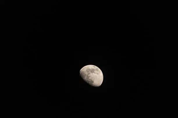 dark night with bright moon rising behind mountain