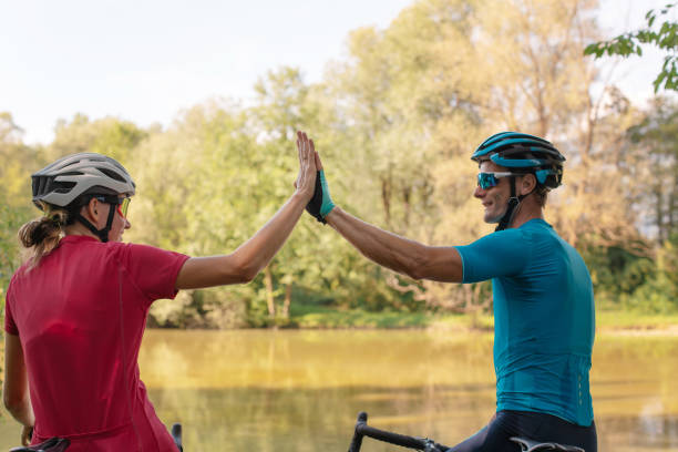 istock Two cyclists high-five each other on a river shoreline 1986160014
