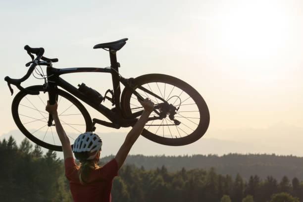 istock Racing female cyclist raising bicycle with both arms above her head 1986163752