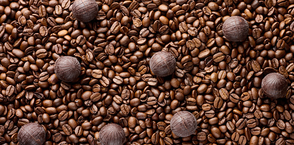 Scattered roasted coffee beans and round chocolate candies